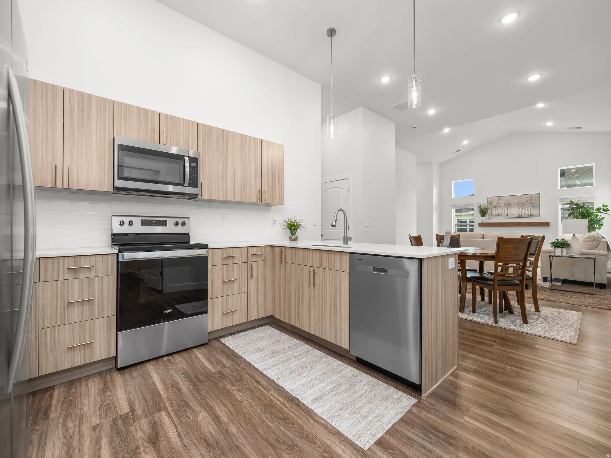Kitchen with Midtone cabinets, tile backsplash, pendant lighting and quartz counters. *Fridge not included