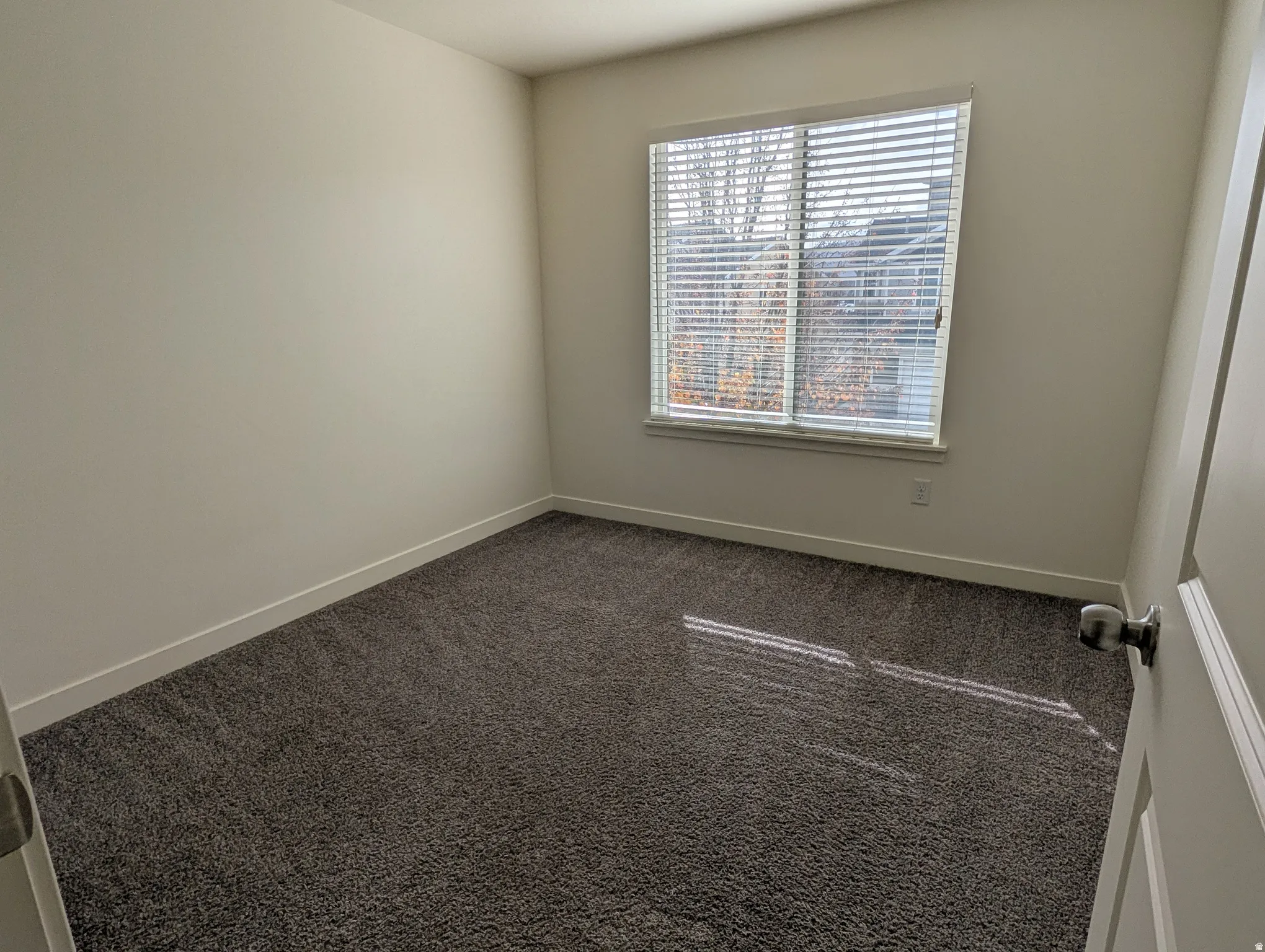 Empty room with dark carpet and baseboards