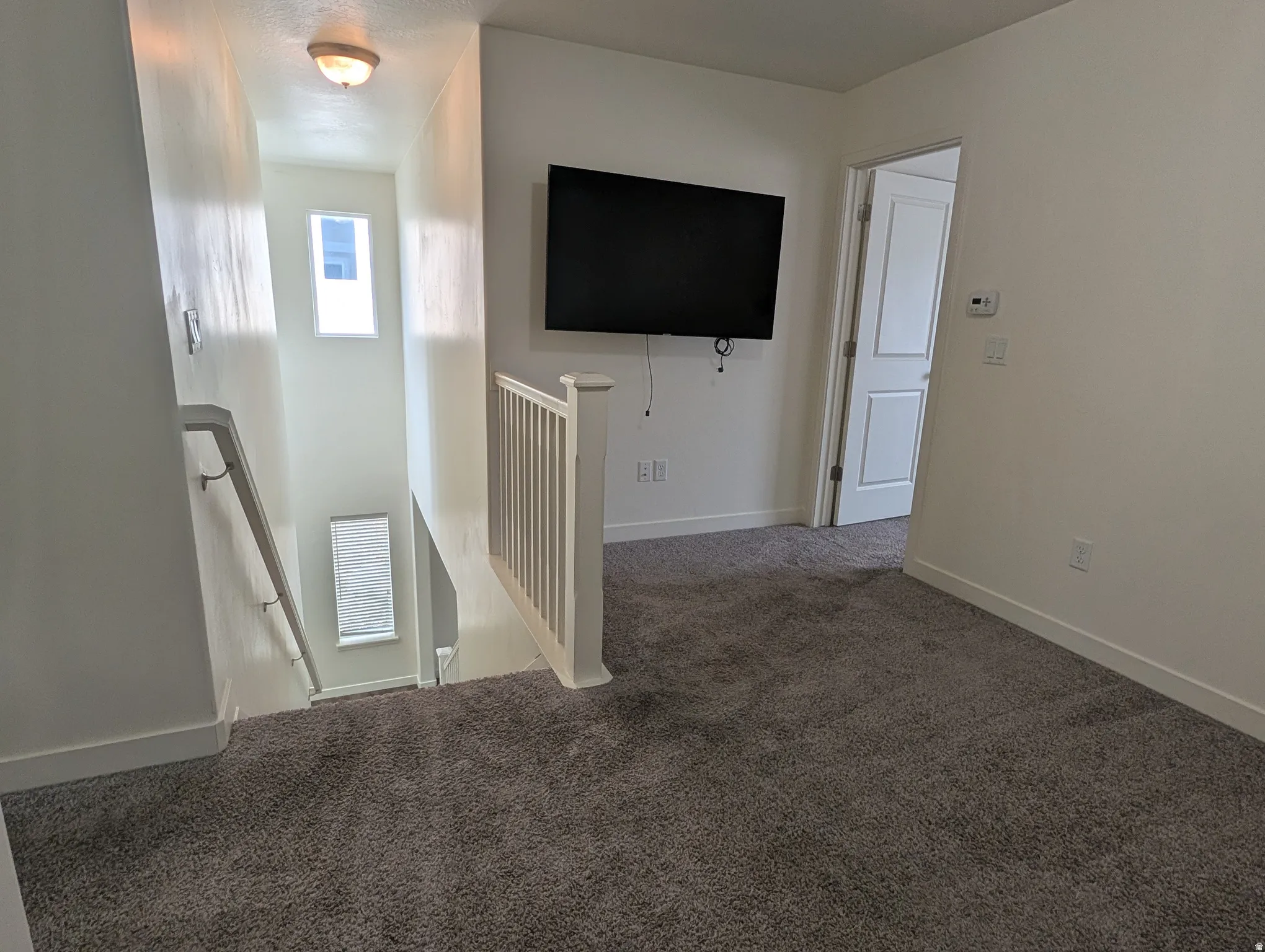 Carpeted spare room featuring baseboards