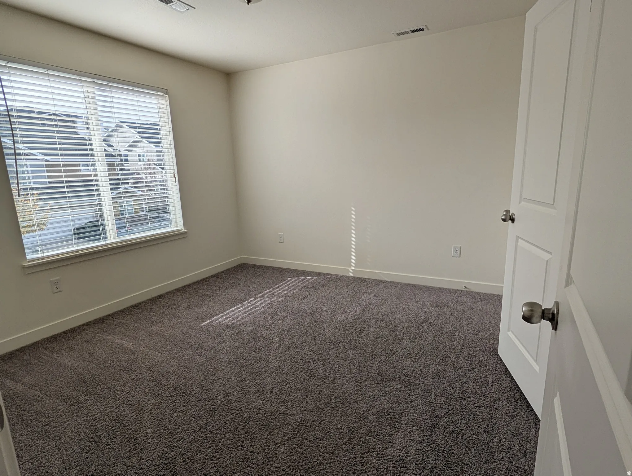 Spare room with dark colored carpet and baseboards