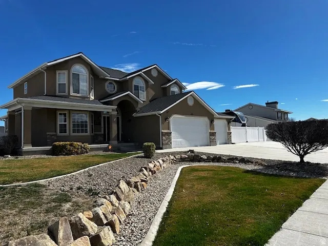 Traditional-style home with an attached garage, stucco siding, and concrete driveway
