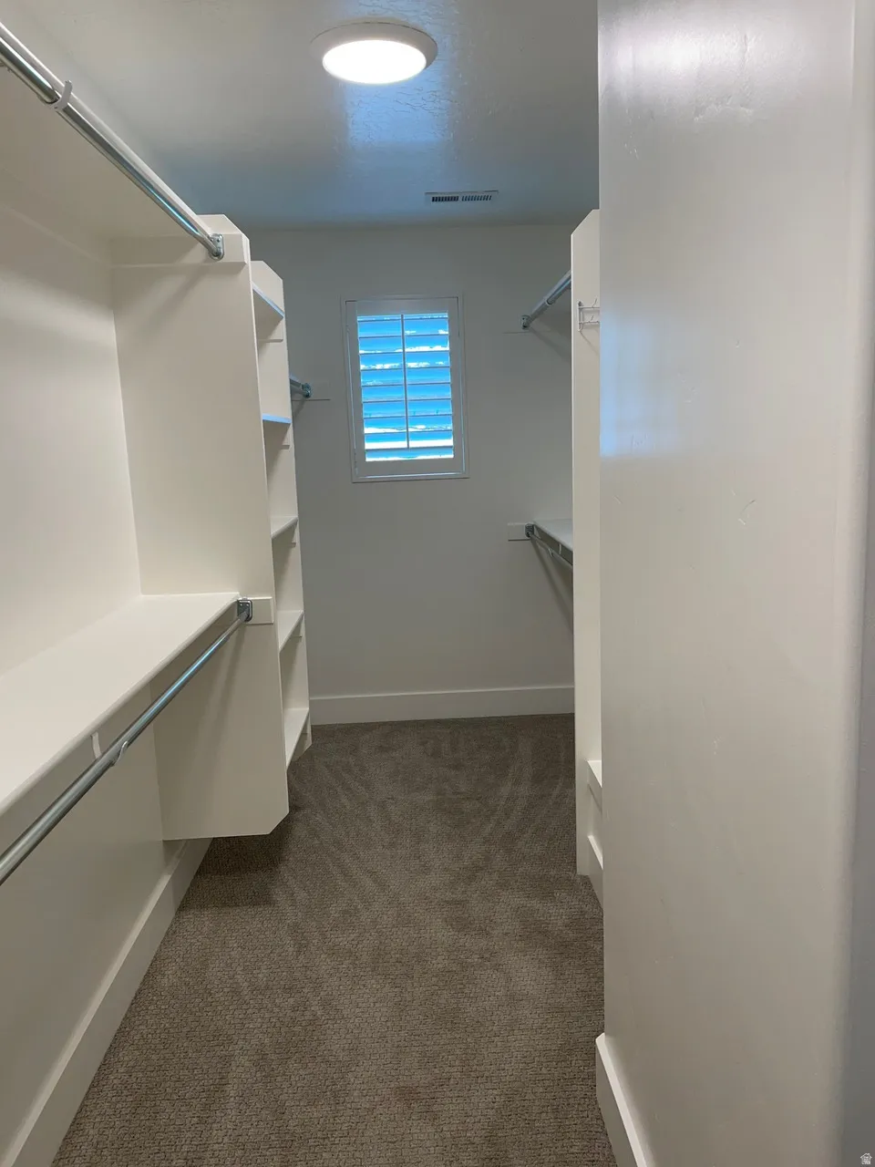 Walk in closet featuring dark colored carpet