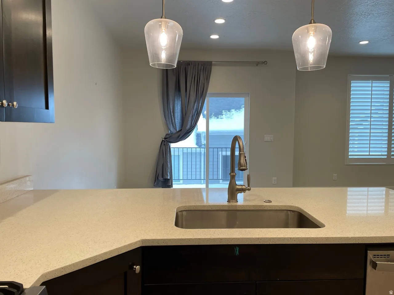 Kitchen featuring light stone countertops, stainless steel dishwasher, and decorative light fixtures