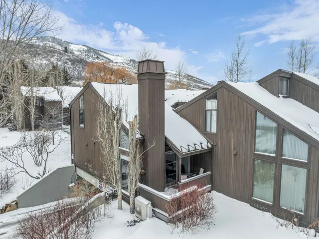 View of snowy exterior featuring a deck with mountain view and a chimney