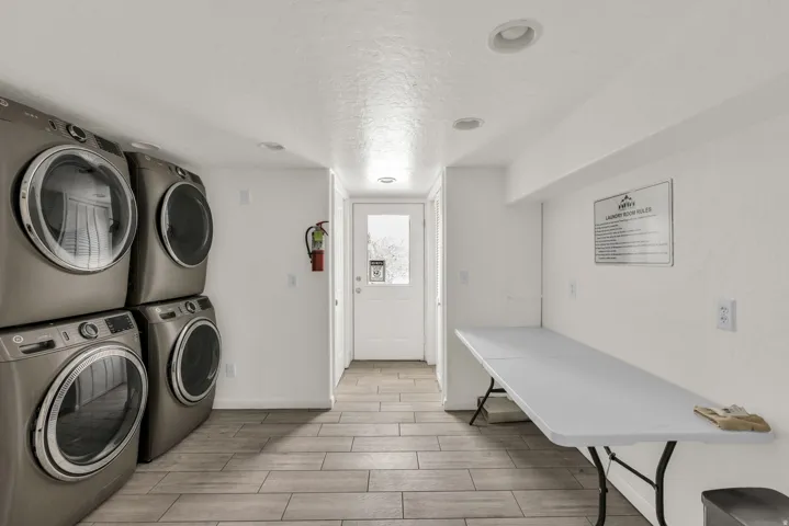 Laundry area featuring a textured ceiling, wood tiled floors, and stacked washer and clothes dryer