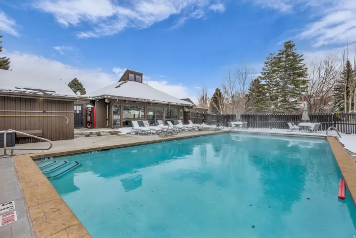 Community pool with a fenced backyard and a patio