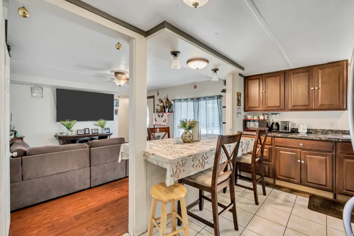 Kitchen with wood finish cabinets, dark stone countertops, open floor plan, and a ceiling fan