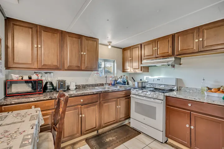Kitchen featuring wood finish cabinetry, white range with gas cooktop, and light tile patterned floors