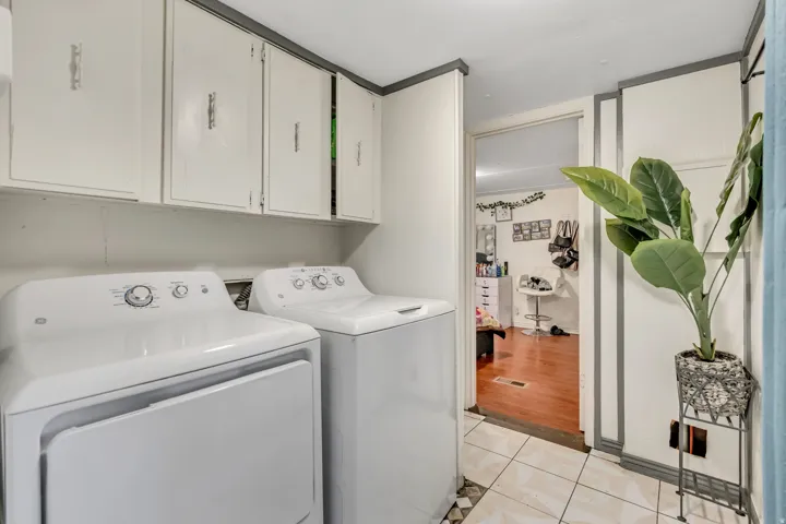 Laundry room featuring light tile patterned floors, cabinet space, and washing machine and clothes dryer