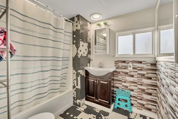 Bathroom featuring vanity, tile patterned flooring, shower / bath combination with curtain, and tile walls