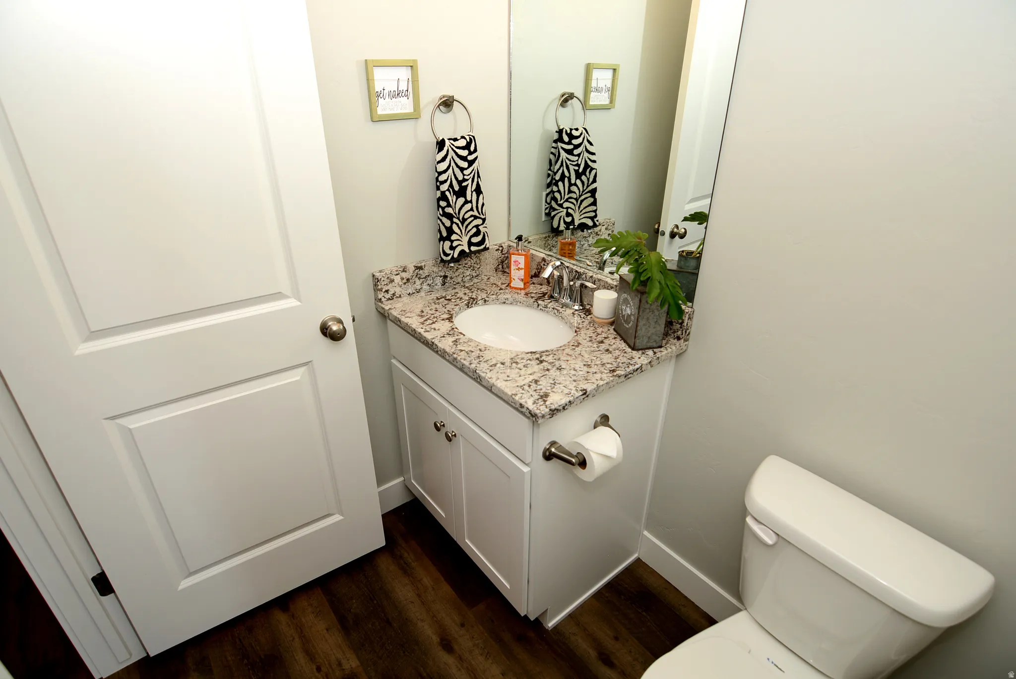 Half bathroom featuring vanity and dark wood-style floors