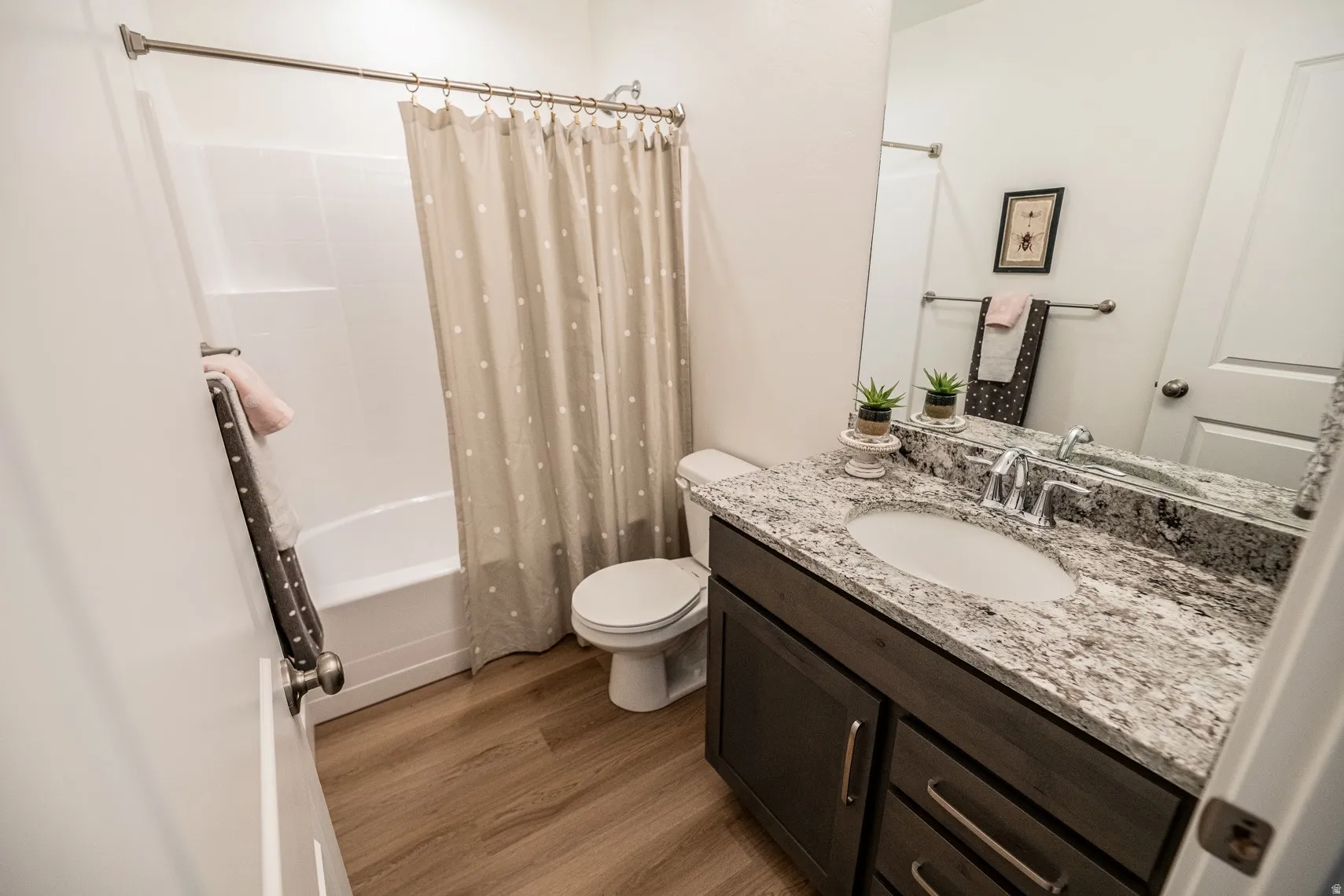 Bathroom featuring vanity, shower / bath combo, and light wood-type flooring