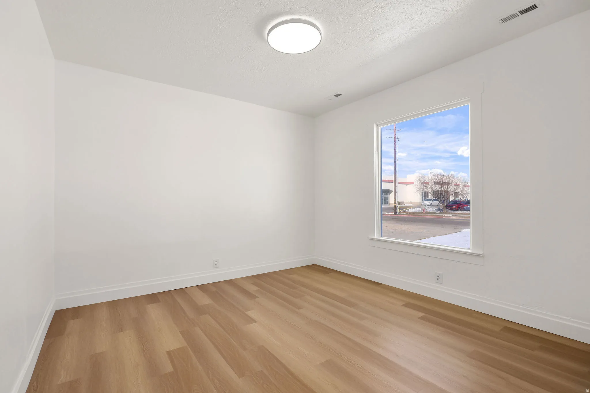 Unfurnished room featuring light wood-style floors and a textured ceiling