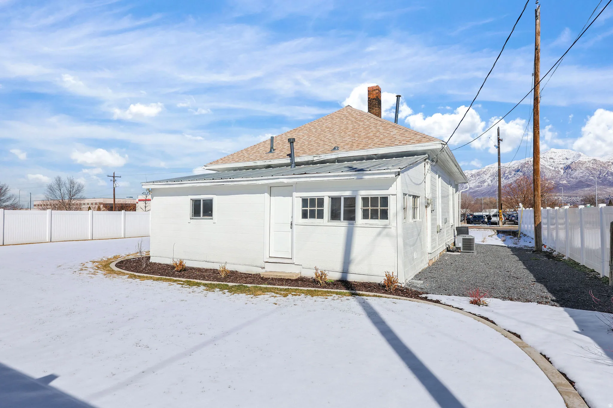 Rear view of house with a fenced backyard, roof with shingles, a chimney, and a mountain view