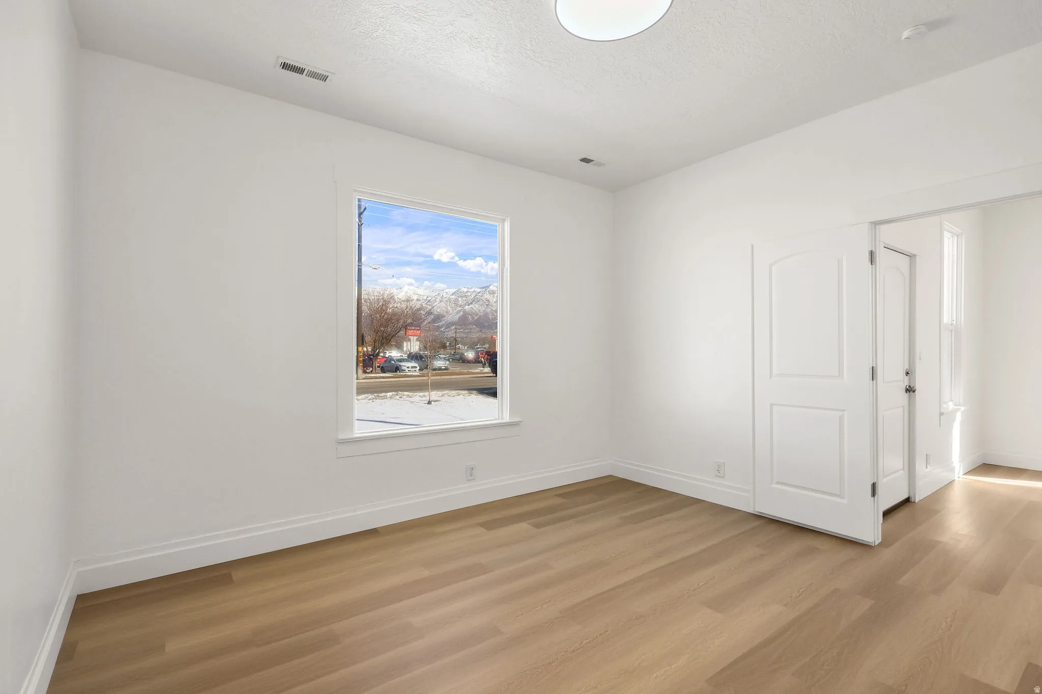 Spare room featuring light wood-type flooring and a textured ceiling