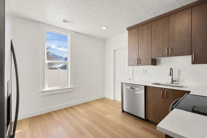Kitchen featuring stainless steel appliances, light wood finished floors, light stone counters, a textured ceiling, and modern cabinets