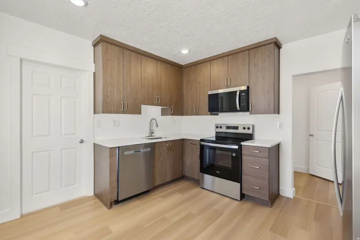 Kitchen featuring stainless steel appliances, modern cabinets, light wood-style flooring, recessed lighting, and light stone countertops