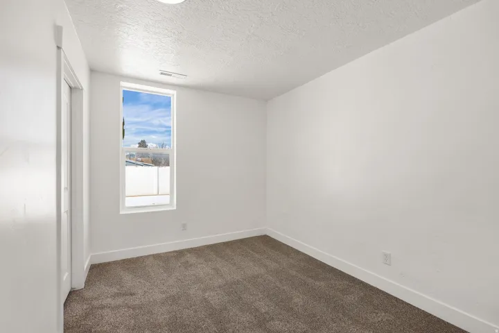 Unfurnished room featuring dark carpet and a textured ceiling