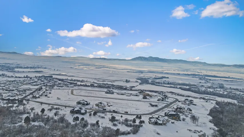 Snowy aerial view featuring a mountain view and a view of countryside