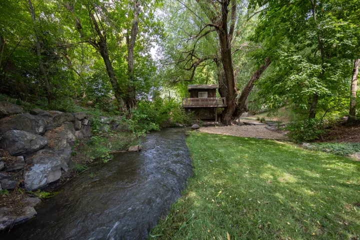View of green lawn with a deck with water view