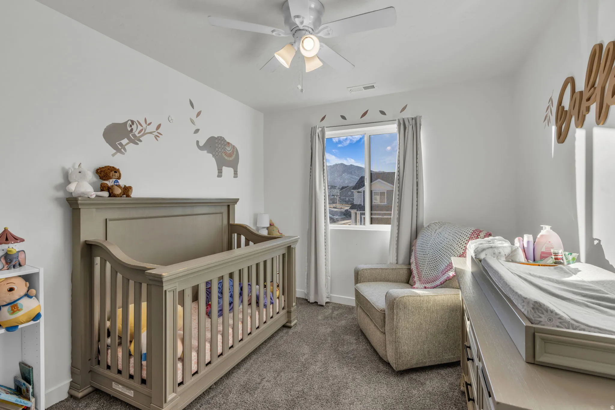Bedroom with a crib, carpet flooring, and ceiling fan