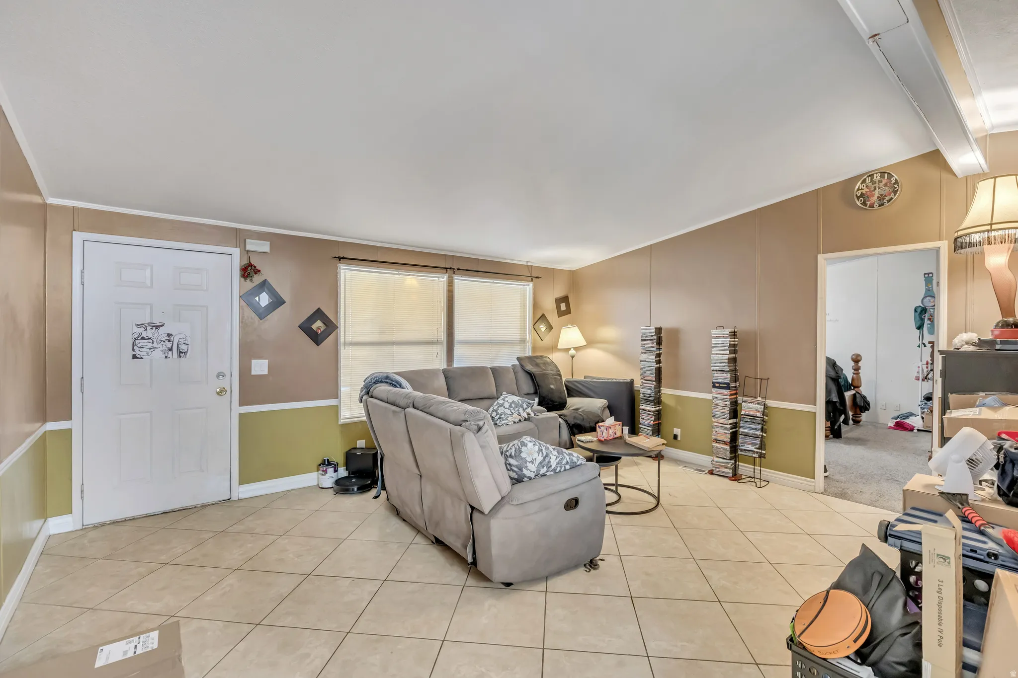 Living area with light tile patterned floors and vaulted ceiling with beams