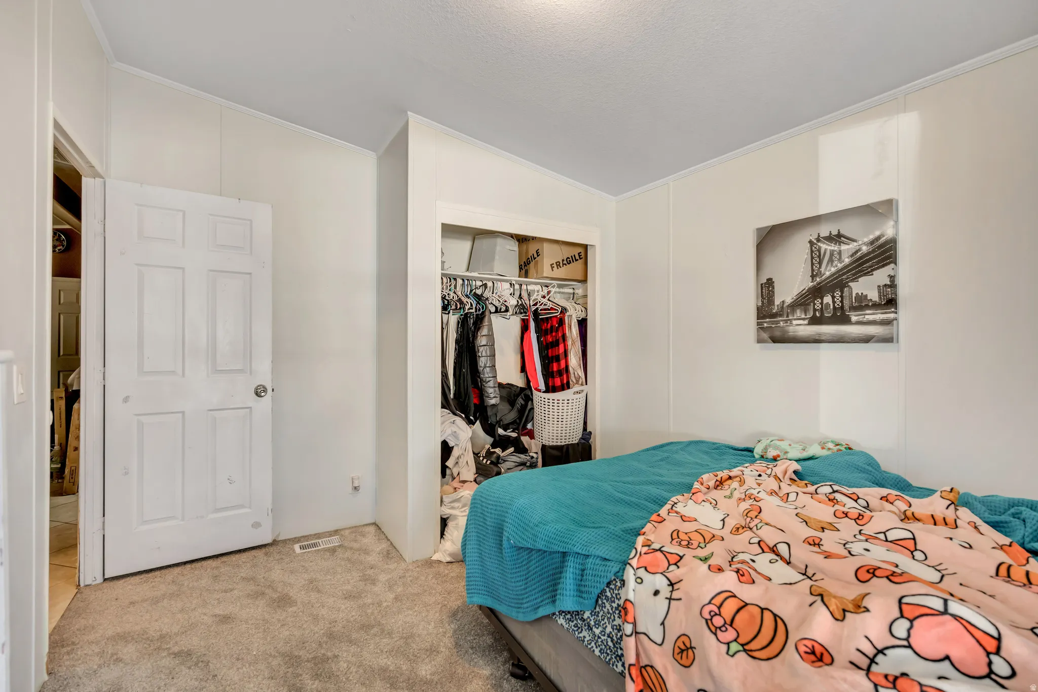 Bedroom with a closet, carpet, ornamental molding, and vaulted ceiling