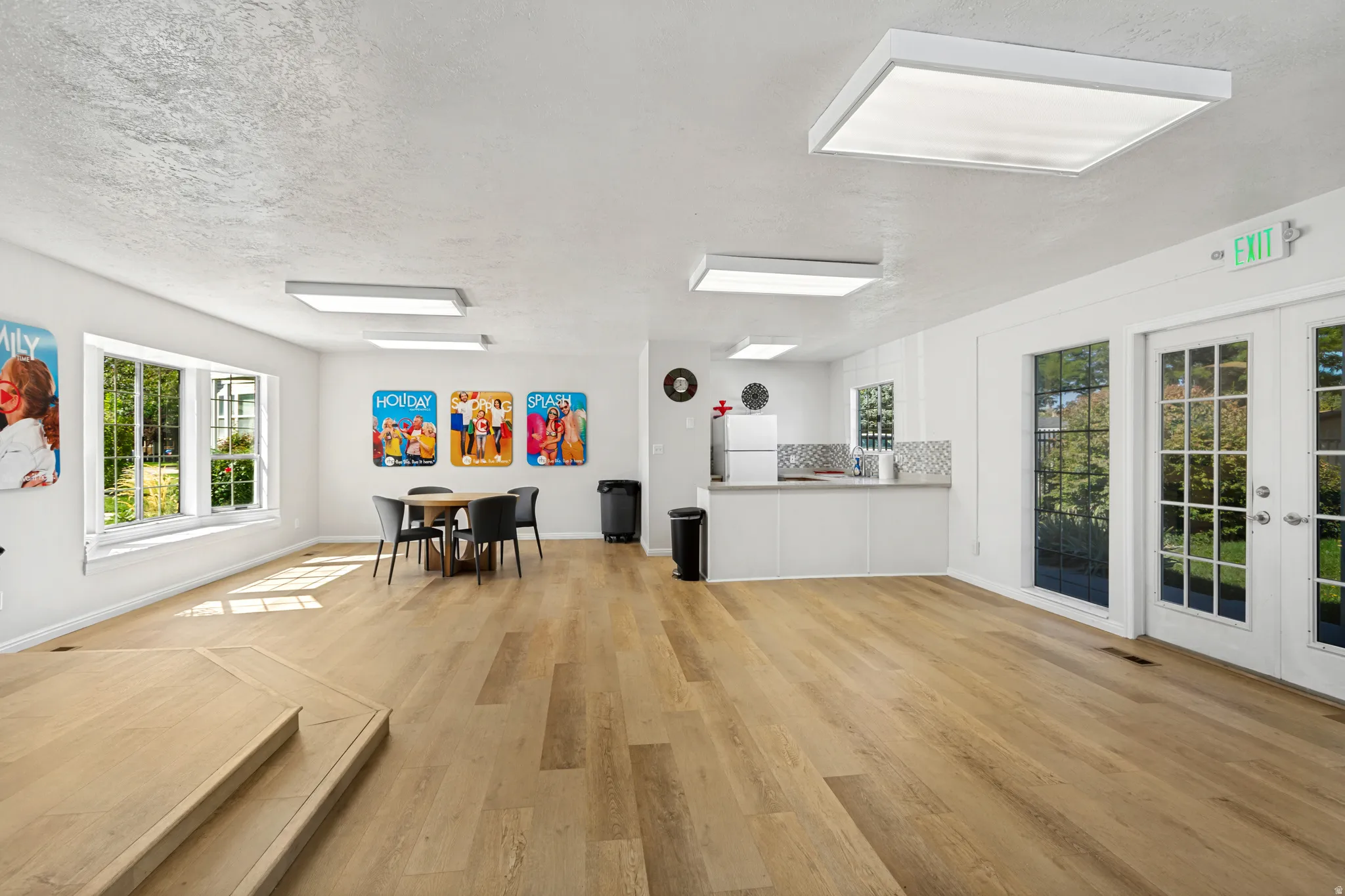 Expansive room featuring wood-finish flooring, multiple windows, a built-in countertop with tiled backsplash, and recessed lighting