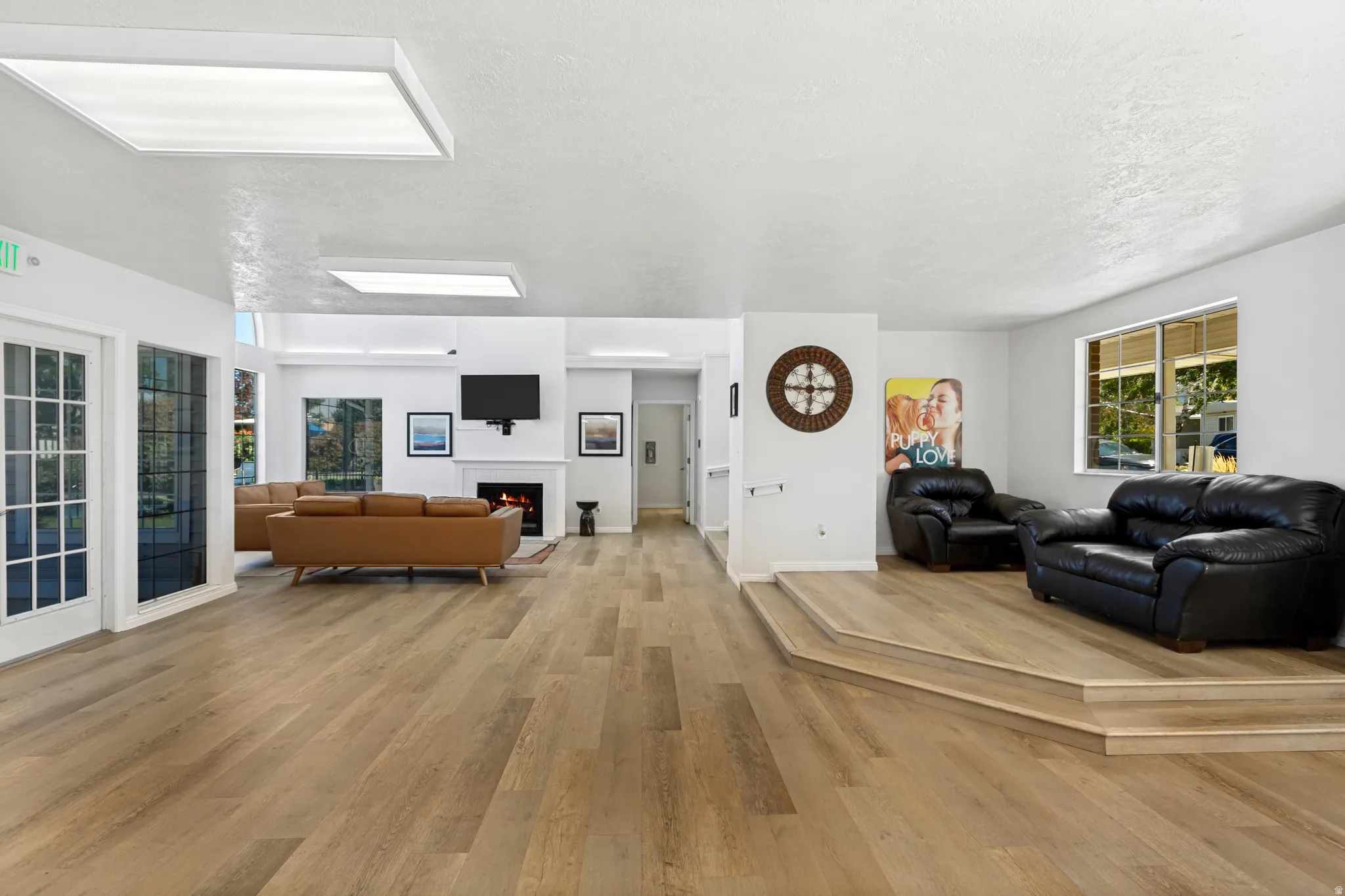 Open concept gathering room with wood-finish flooring, a contemporary fireplace, and recessed lighting