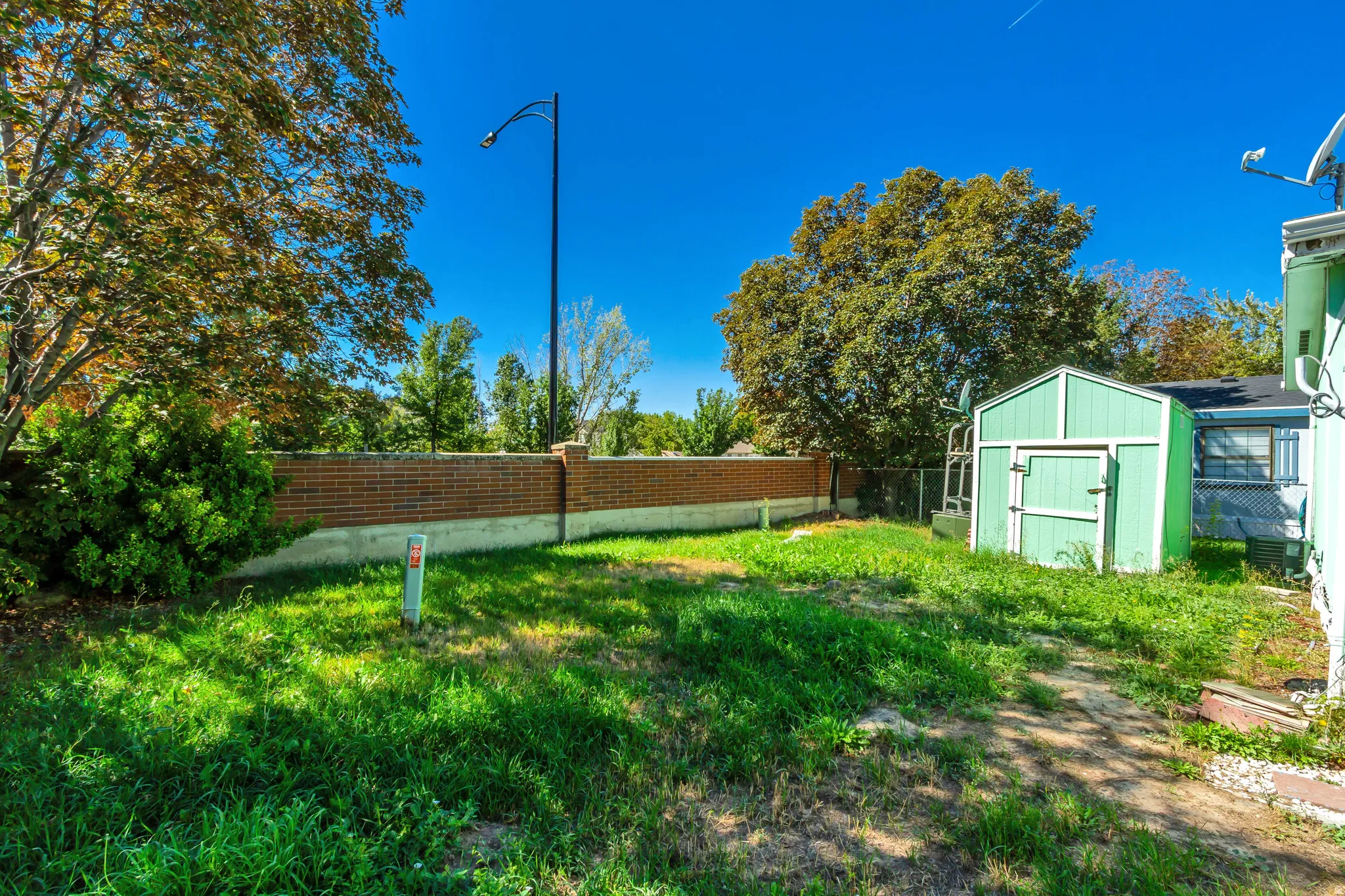 Expansive backyard featuring a brick retaining wall and a storage shed