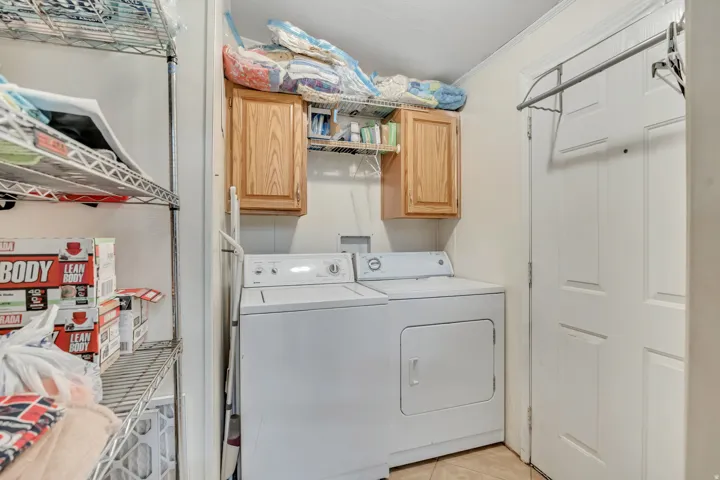 Laundry room featuring independent washer and dryer, crown molding, cabinet space, and light tile patterned flooring
