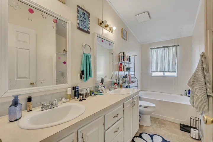 Full bath with double vanity, ornamental molding, and a bath