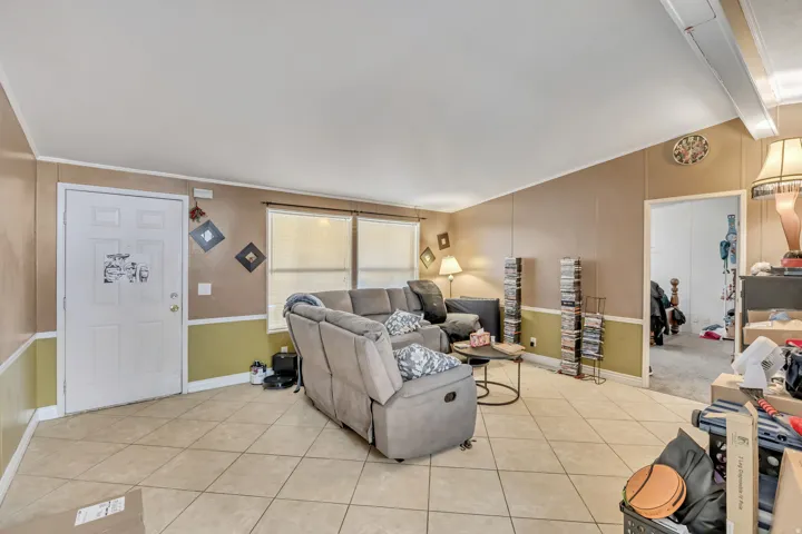 Living area with light tile patterned floors and vaulted ceiling with beams