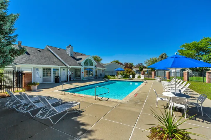 Outdoor swimming pool with concrete surround, featuring an adjacent building with gabled roof lines and arched window