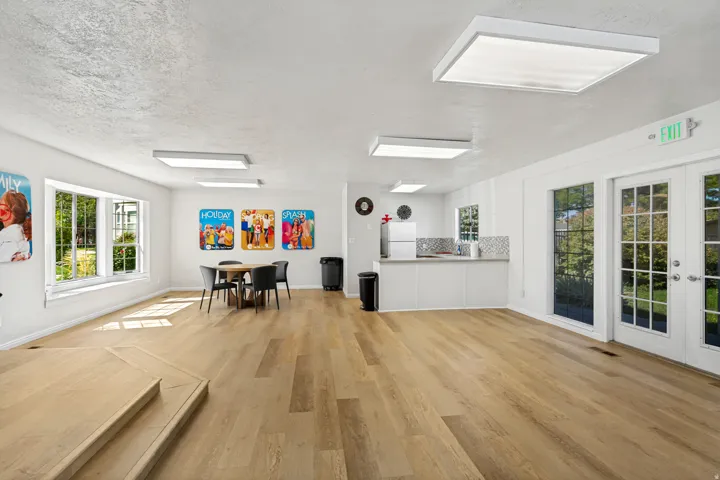 Expansive room featuring wood-finish flooring, multiple windows, a built-in countertop with tiled backsplash, and recessed lighting