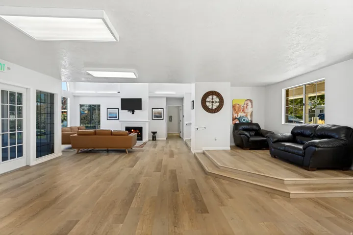 Open concept gathering room with wood-finish flooring, a contemporary fireplace, and recessed lighting