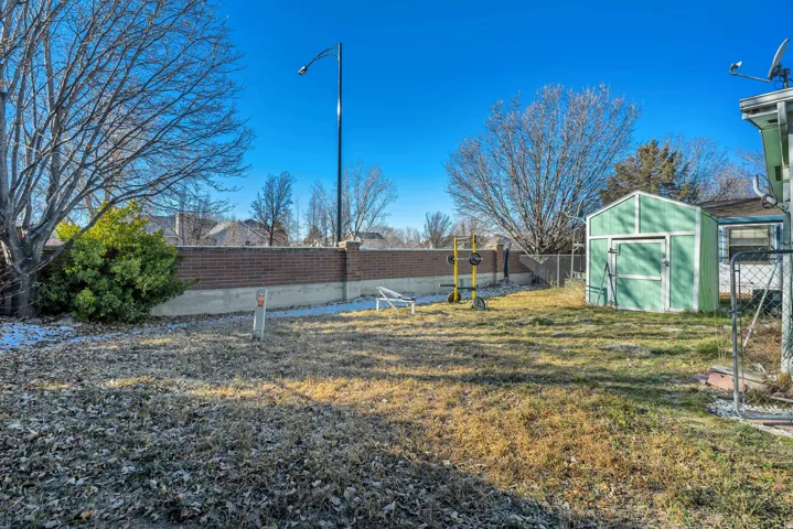 Fenced backyard featuring a storage unit