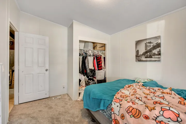 Bedroom with a closet, carpet, ornamental molding, and vaulted ceiling