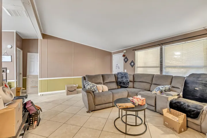 Living area featuring tile patterned floors, a decorative wall, and vaulted ceiling
