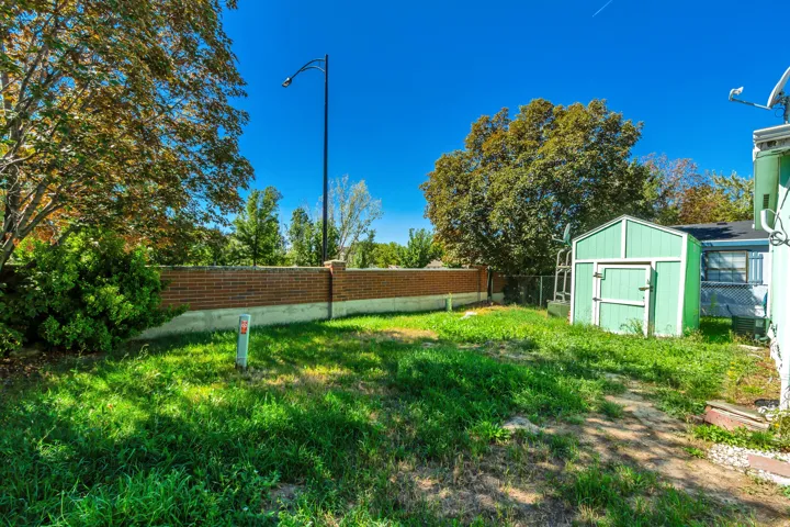 Expansive backyard featuring a brick retaining wall and a storage shed