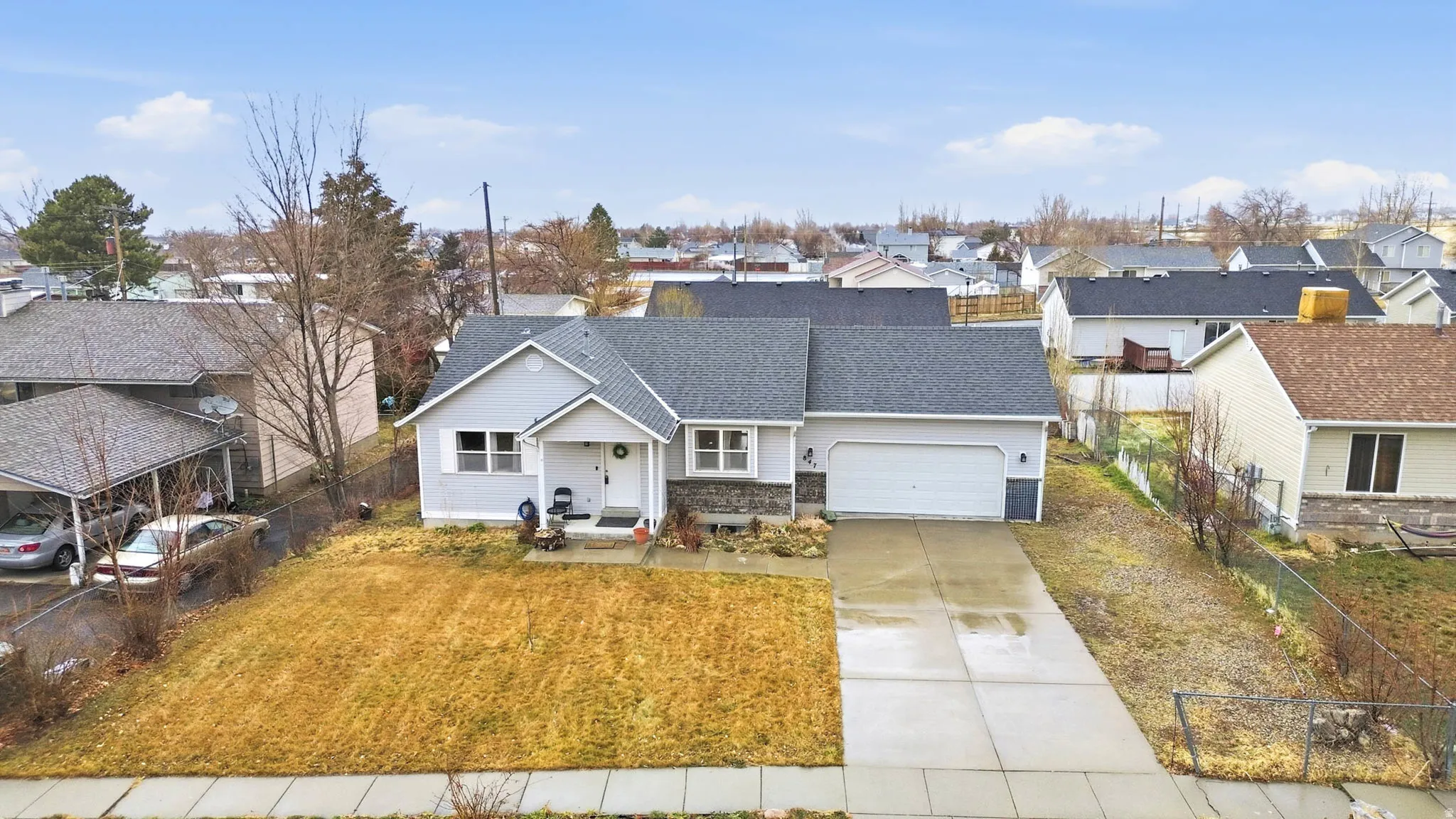 View of front facade featuring concrete driveway, a residential view, an attached garage, and roof with shingles