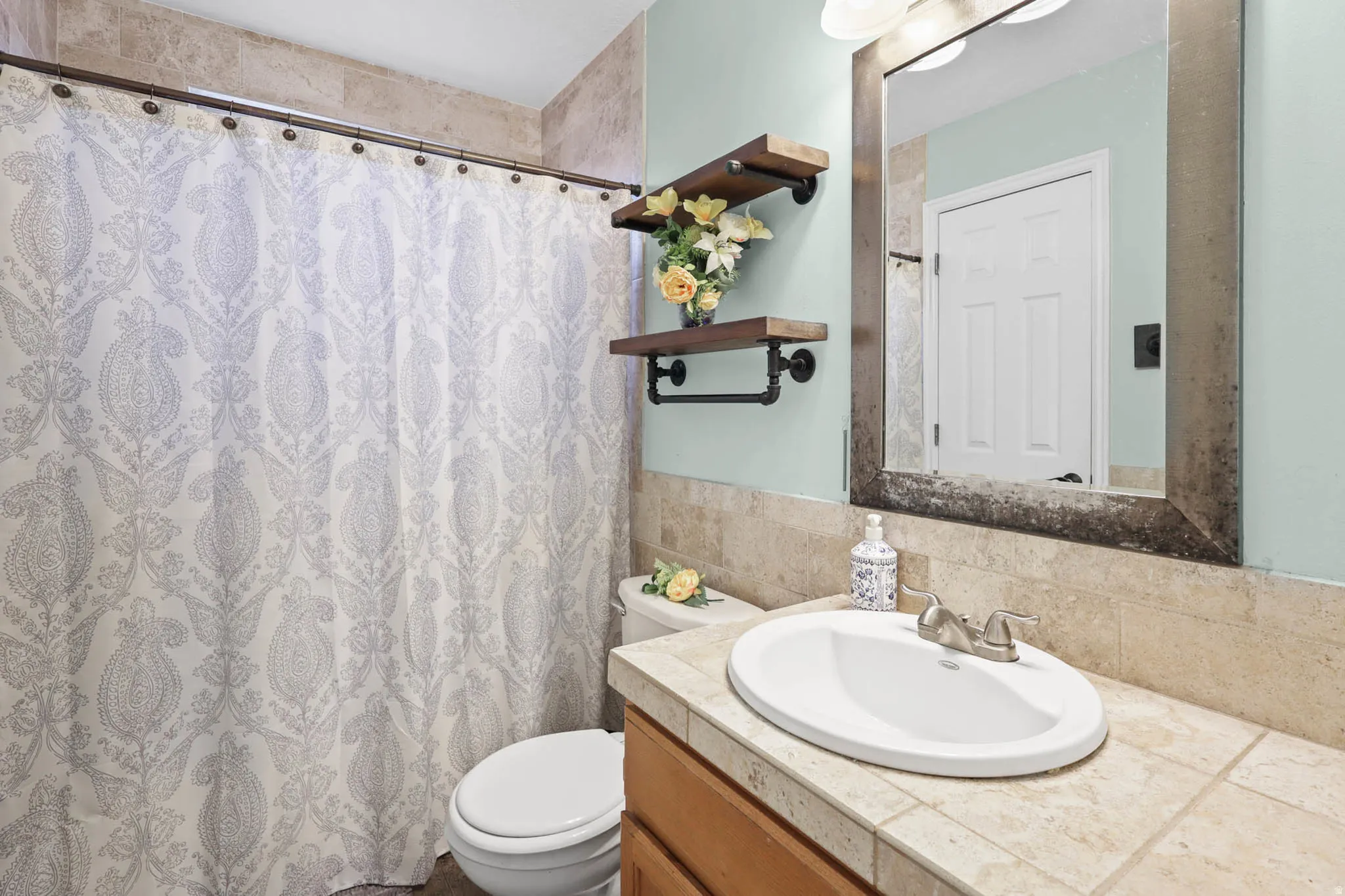 Bathroom with vanity, a shower with curtain, and tasteful backsplash