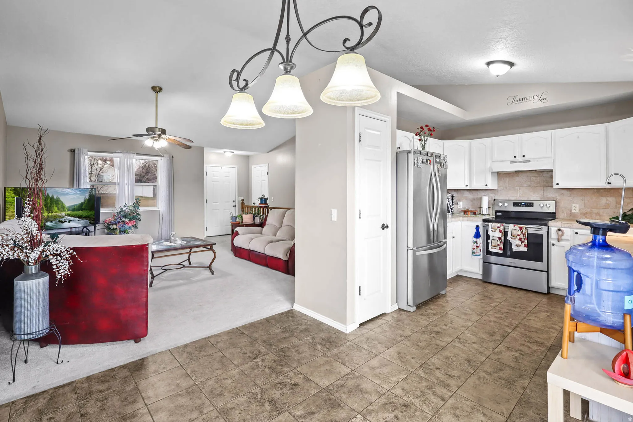 Kitchen with light countertops, white cabinetry, dark carpet, stainless steel appliances, and a ceiling fan