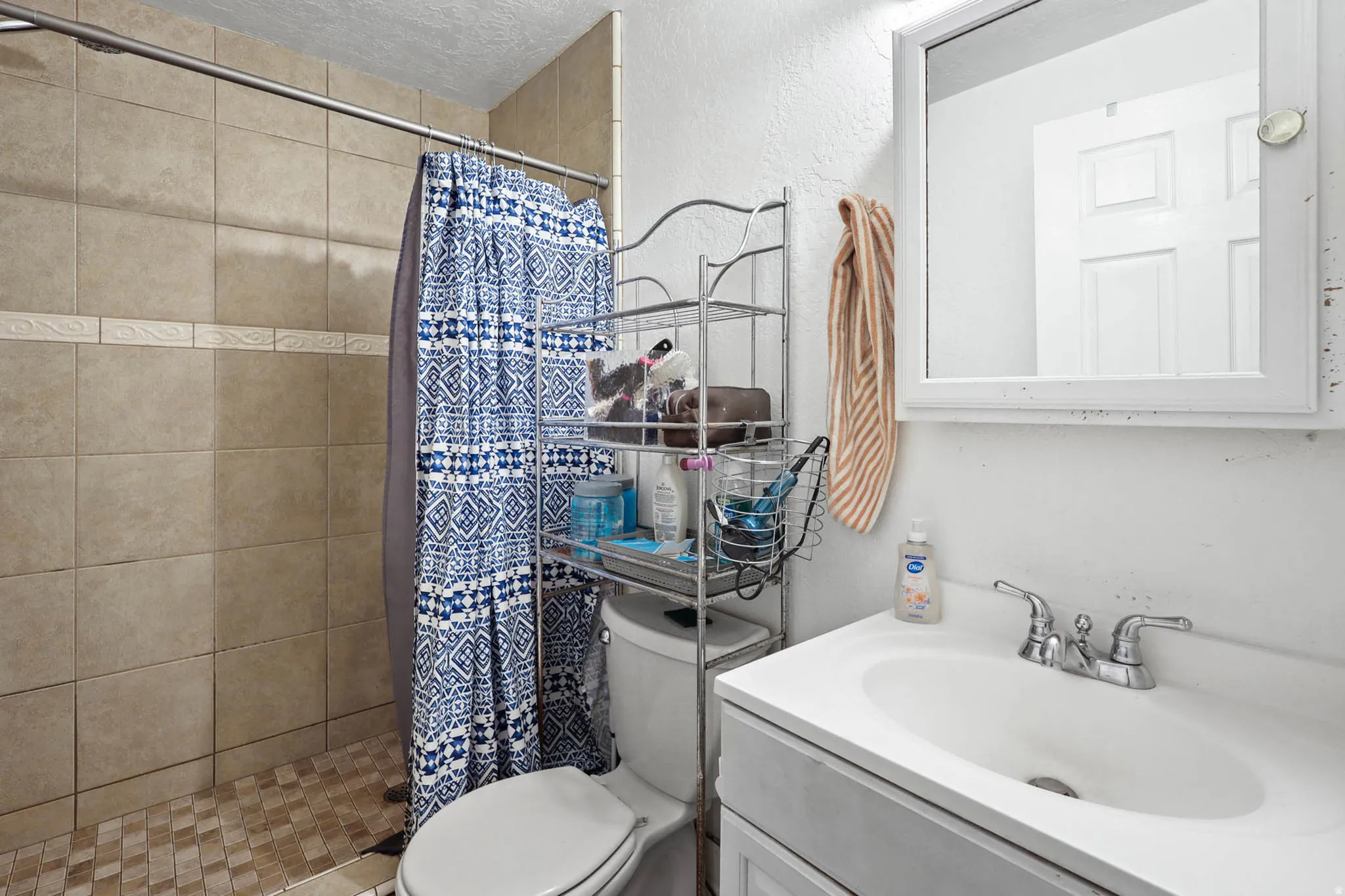 Full bath featuring vanity, a stall shower, a textured ceiling, and a textured wall
