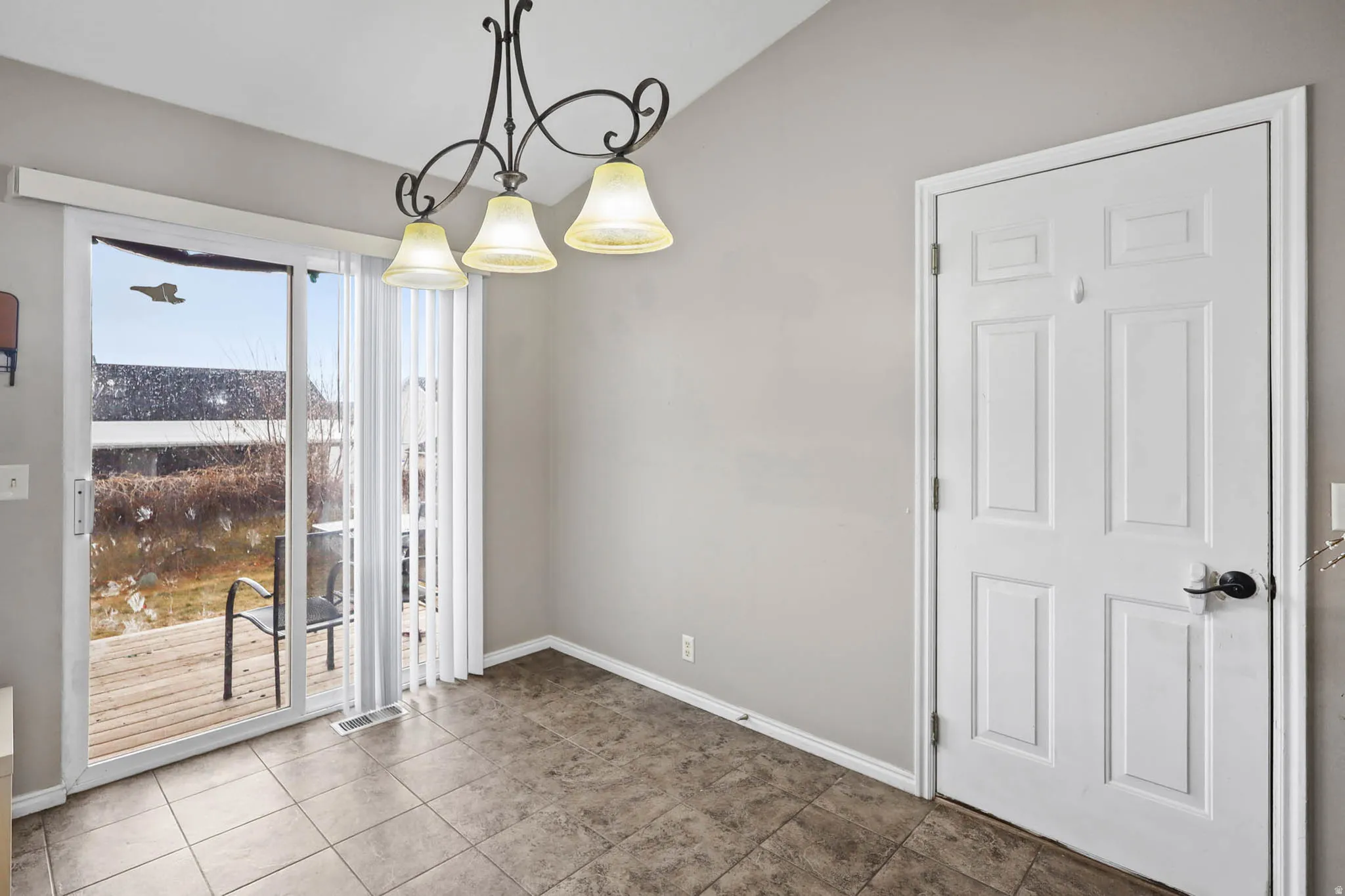 Unfurnished dining area with vaulted ceiling and tile patterned floors