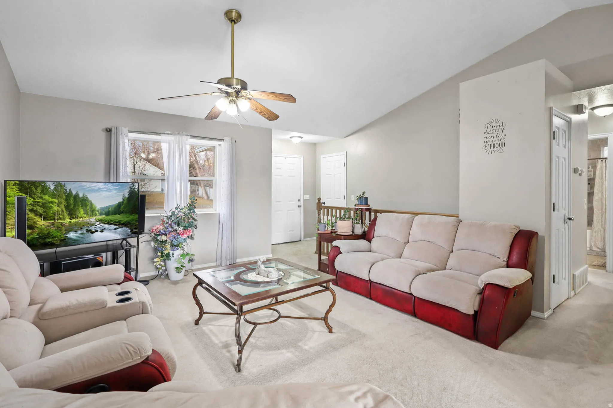 Carpeted living area featuring vaulted ceiling and ceiling fan
