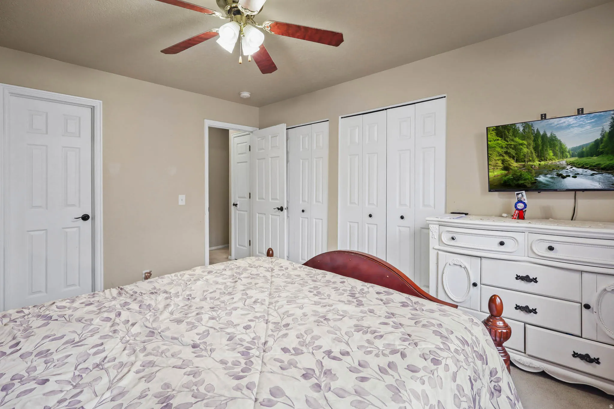 Carpeted bedroom with multiple closets and a ceiling fan