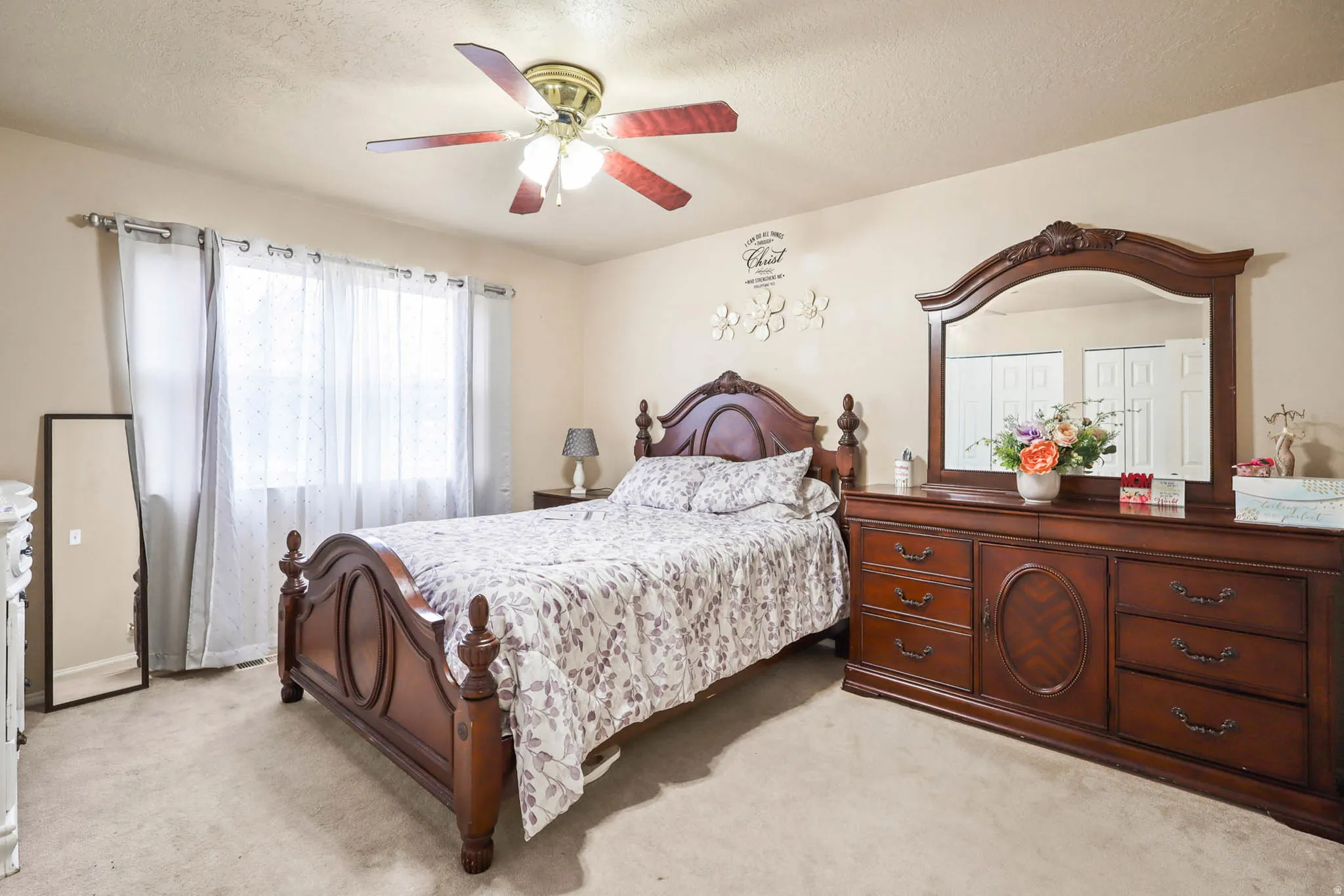 Bedroom with light carpet, a textured ceiling, and ceiling fan