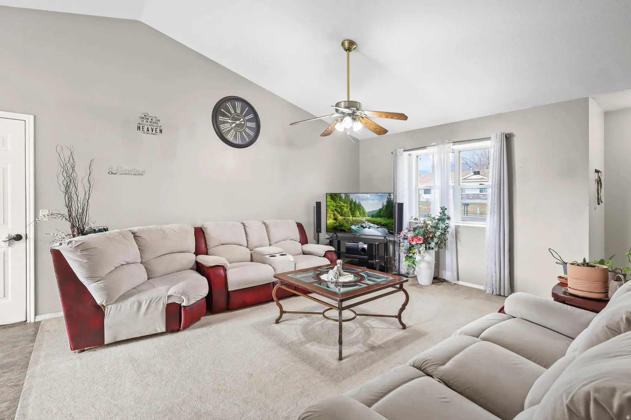 Living room with vaulted ceiling, a ceiling fan, and carpet flooring