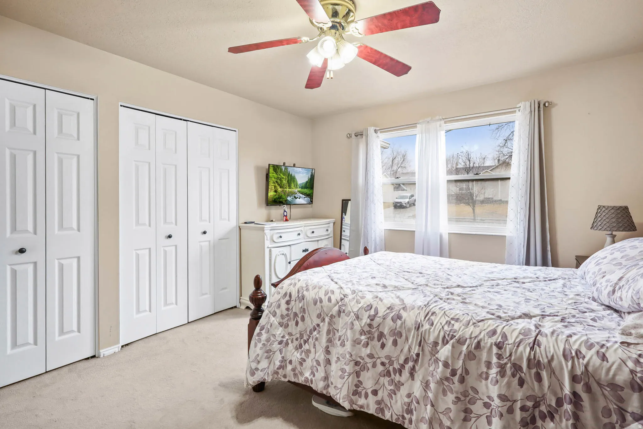 Bedroom featuring two closets, light carpet, and a ceiling fan